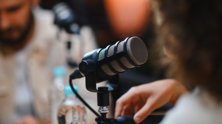 Two people recording a business podcast with microphones in a professional studio.