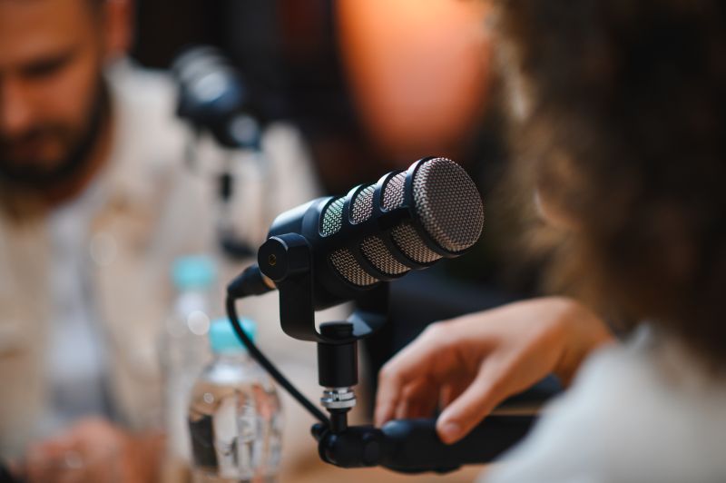 Two people recording a business podcast with microphones in a professional studio.