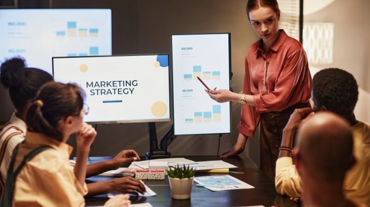 Marketing professional presenting campaign performance data to colleagues during a marketing strategy meeting