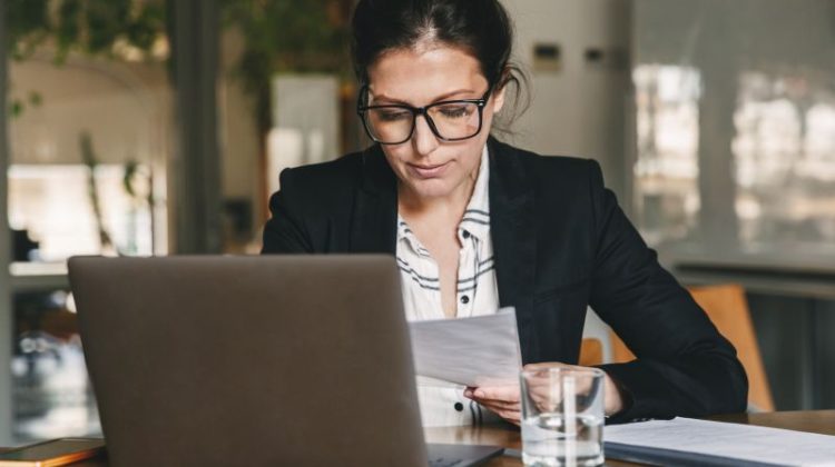 Businesswoman working on a laptop with her smartphone nearby, illustrating the challenge of switching off from work.