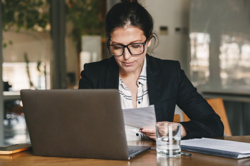 Businesswoman working on a laptop with her smartphone nearby, illustrating the challenge of switching off from work.