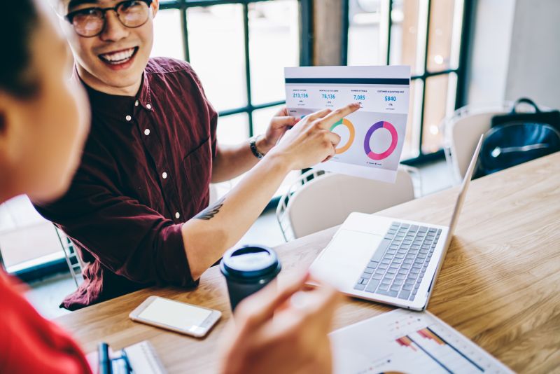 Smiling coworkers checking graph in office