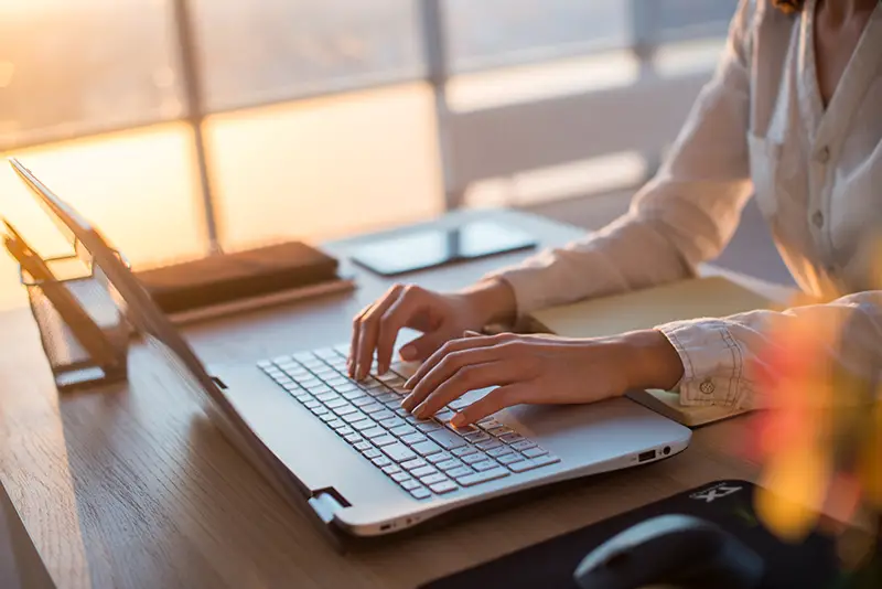 Concentrated female employee typing at workplace using computer.