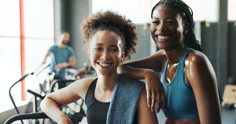 Fitness, portrait and smile of woman friends in gym together for break from training or workout.