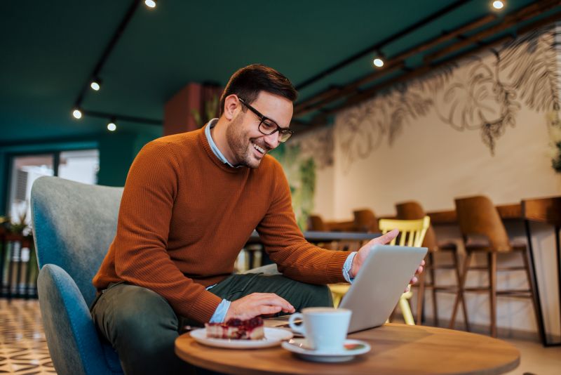 Smiling businessman using laptop in the cafe and relaxing, portrait.