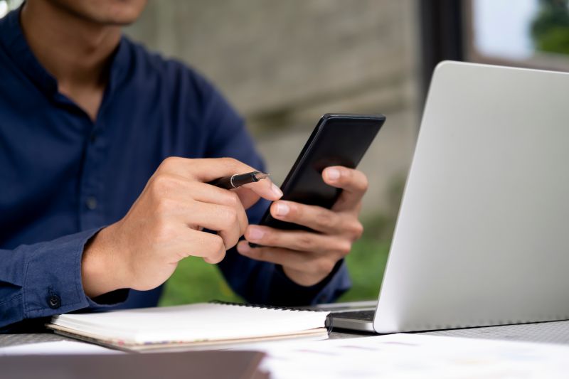 Professional Using Smartphone and Laptop at Workplace