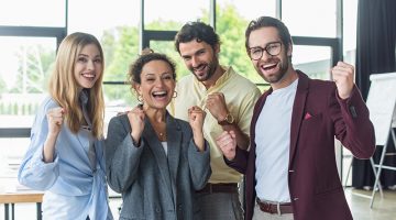 Excited interracial business people showing yes gesture at camera in office