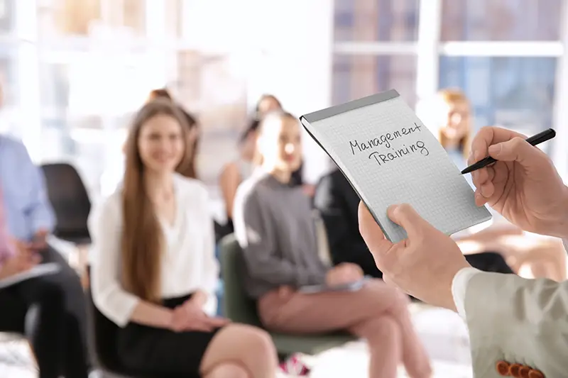 Business trainer holding notebook with text MANAGEMENT TRAINING