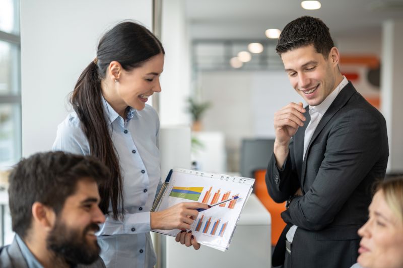 Business people discussing profit, revenue, market share, customer satisfaction and other indicators of performance of company growth from graphs at meeting in the office.