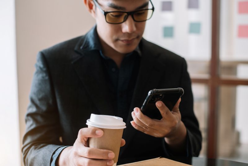 Business men hand holding smartphone device in cafe.