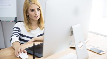 Casual young female photo editor working on computer in office