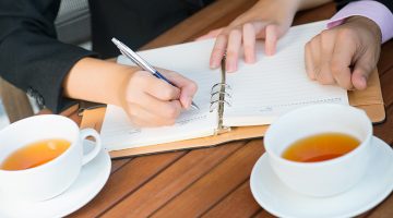 Close-up of colleagues planning their daily business activity over tea