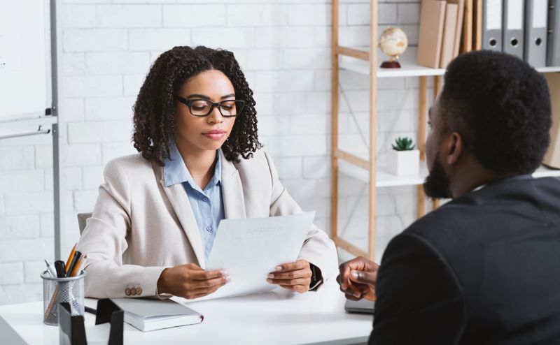 Focused female HR manager studying vacancy applicant's CV during employment interview at office