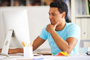 Smart guy sitting at workplace and working with computer