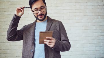 Male employee in eyeglasses looking at page of notepad