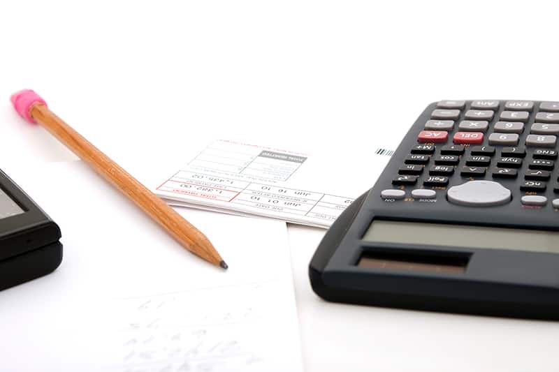 Adding up the monthly expenses for household accounting. A calculator pencil and paperwork. isolated over white.