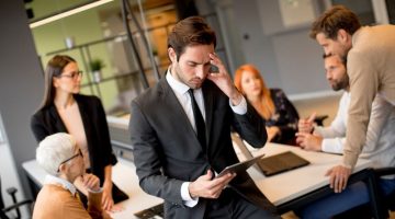 Worried young businessman using digital tablet in office