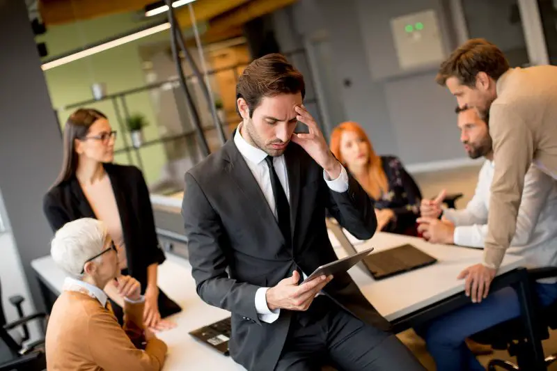 Worried young businessman using digital tablet in office