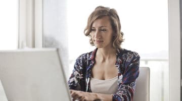 woman in blue floral top sitting while using laptop