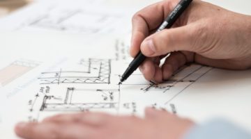 Person holding pen drawing plans