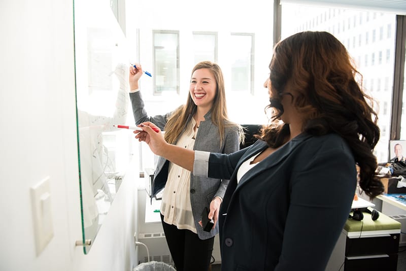 Two women in front of dry erase board