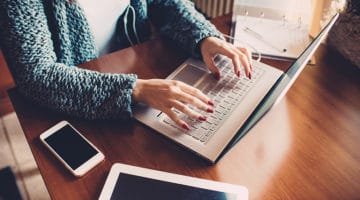 Close up on the hands of young woman using computer, tablet and smart phone - business, technology, multitasking concept