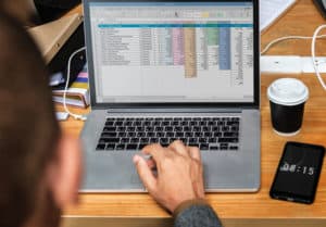 Open laptop with data spreadsheet and coffee cup on desk
