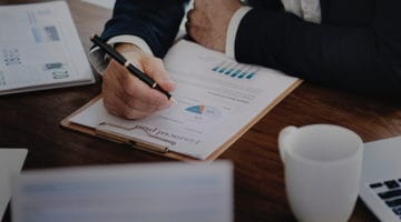 Person holding black twist pen reviewing financial plan