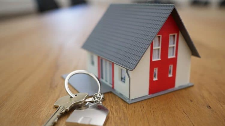 Property Management white and red wooden house miniature on brown table next to a property key