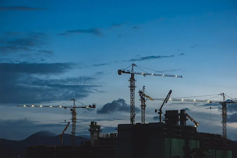 several cranes above buildings on construction site