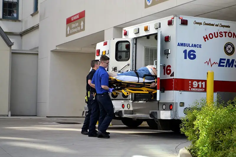 Two paremedics putting a patient into an ambulance.

