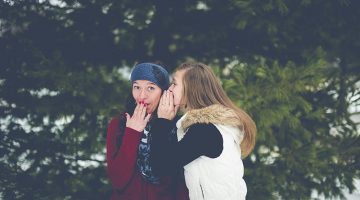 two women wispering - referral - word or mouth