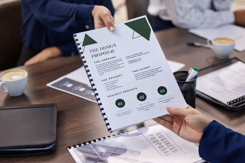 Hands, documents and design proposal by business people in meeting for creative collaboration.