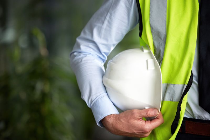 Closeup shot of a white construction helmet being held by an unrecognizable male engineer.