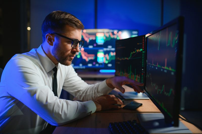 Crypto trader investor analyst looking at computer screen analyzing financial graph data on pc monitor