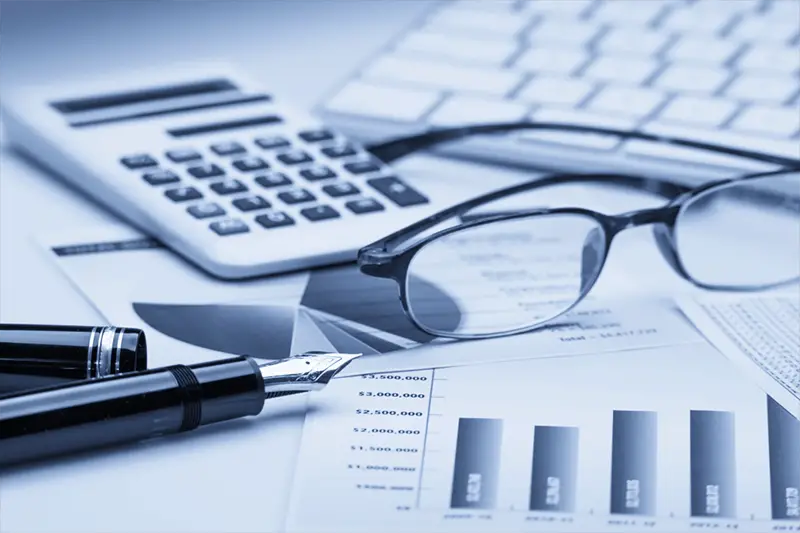 Accounting documents next to calculator eye glasses pen and keyboard