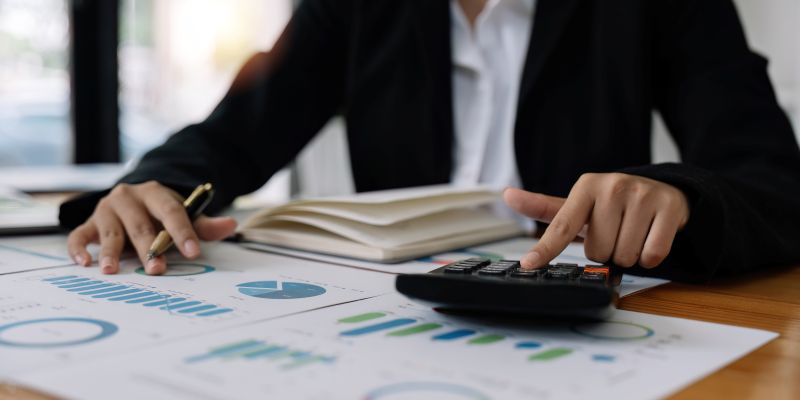 Close up hands of a business accountant woman using a calculator to analysis financial accounts