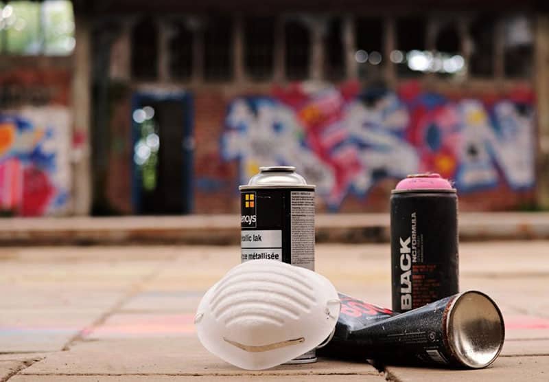 spray paint cans and masks with painted wall inbackground - vandalism