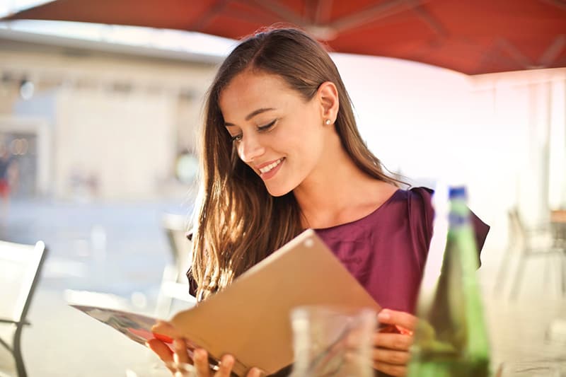 Smiling woman reading menu in restaurant