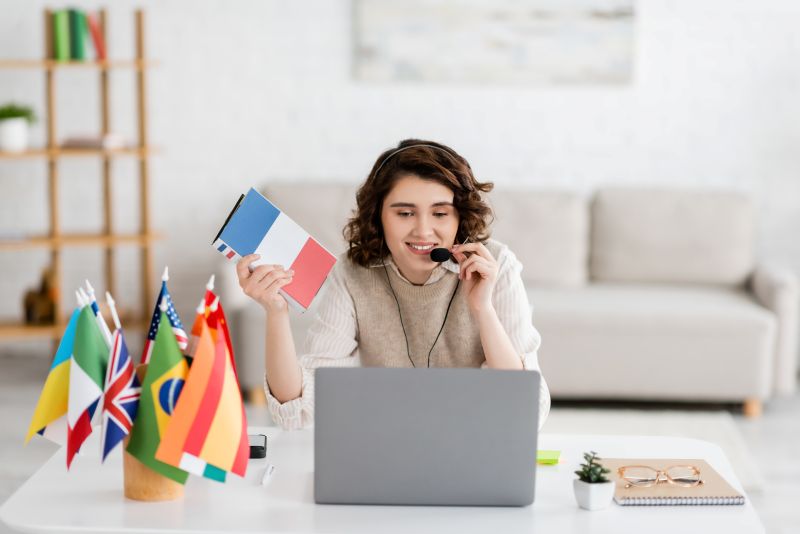 Woman Teaching Languages Online with Flags and Laptop