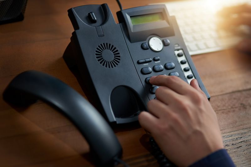 Hand Dials Number on Office Telephone