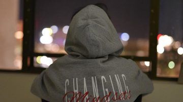 Person wearing a hoodie that says Changing Mindsets - Don't go with the rest of the world, change your mindset to be different