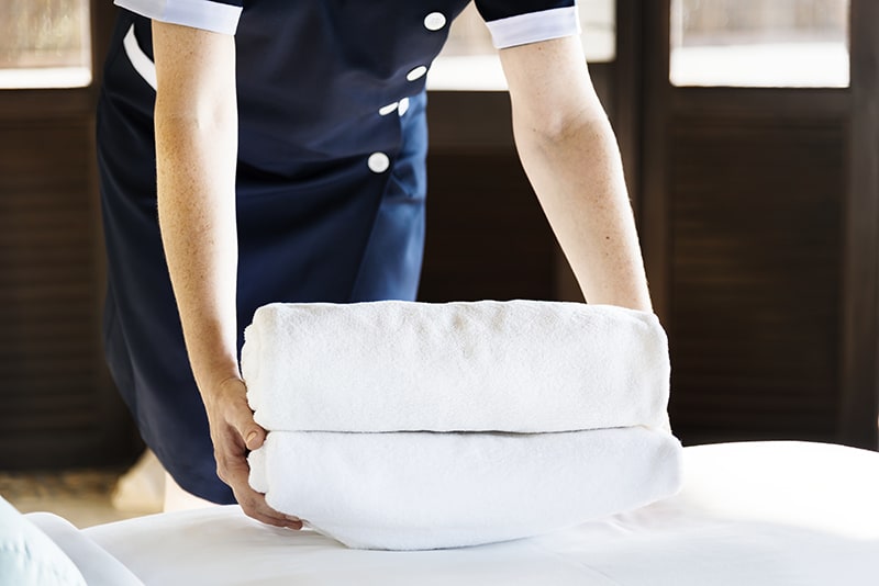 A housekeeper folding and arranging the bed sheets