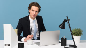 A businessman on his desk, wearing black suit in front of his laptop