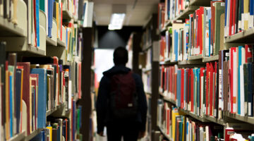 A man with backpack standing in the library