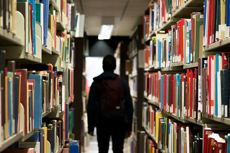 A man with backpack standing in the library