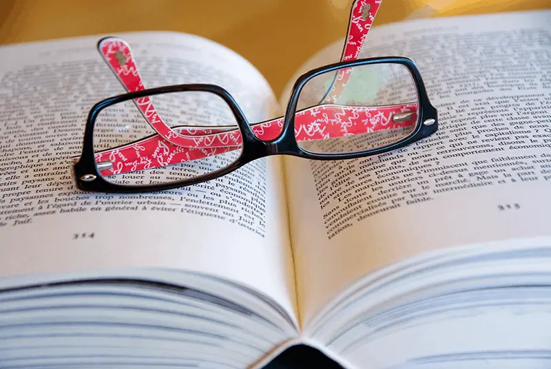 a pair of black and red eyeglasses resting on an open book