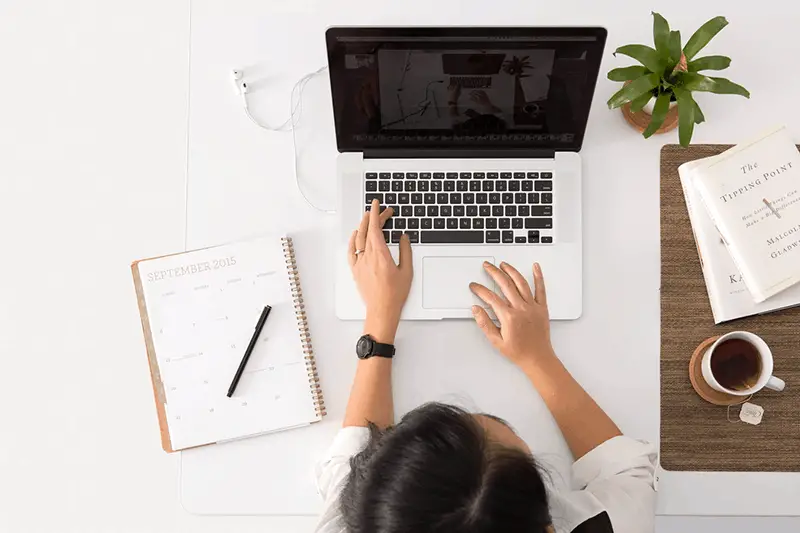 A woman on white tops in front of her laptop