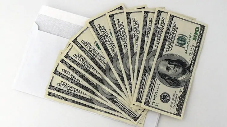 Fan of 100 USA dollar bills on top of an envelope