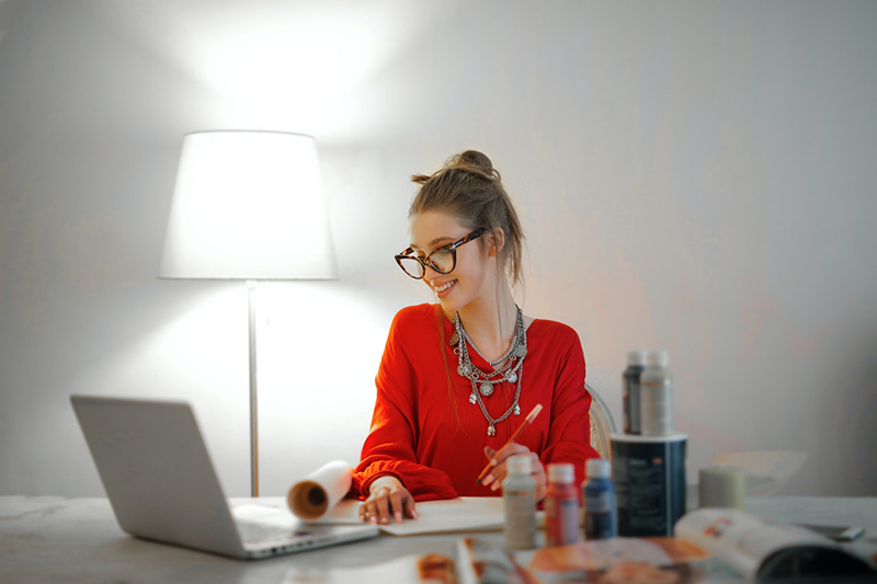 woman wearing red long sleeved top working from home – looking at her computer